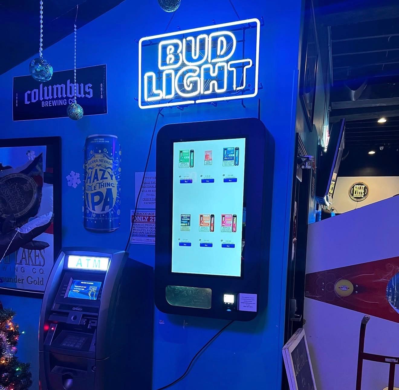 Touchscreen vending machine wall-mounted in a bar with neon lights